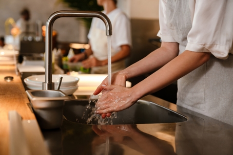woman at a restaurant kitchen washing hands